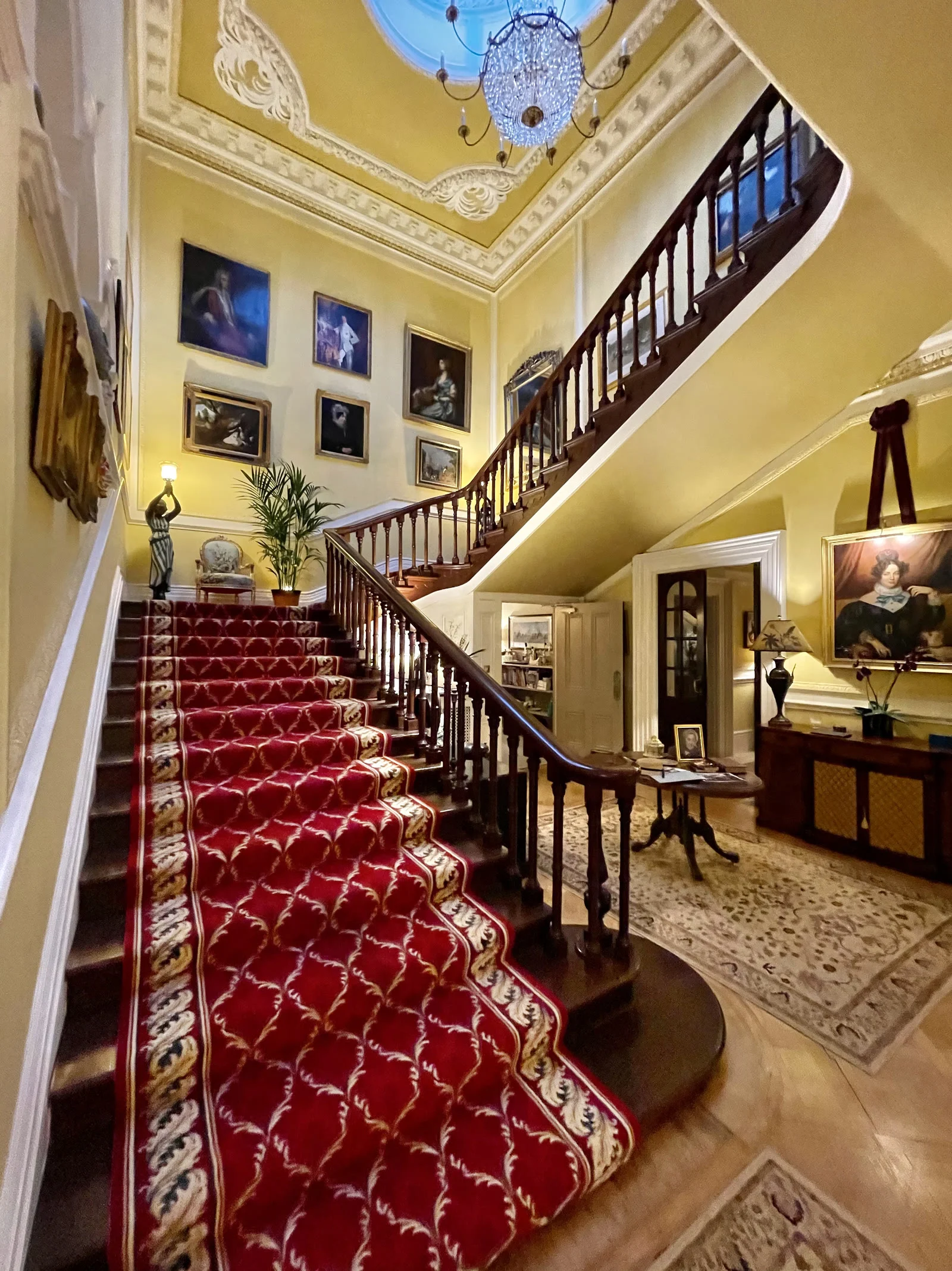 The main staircase at Wylam House &mdash; portraits rising to the stained-glass landing
